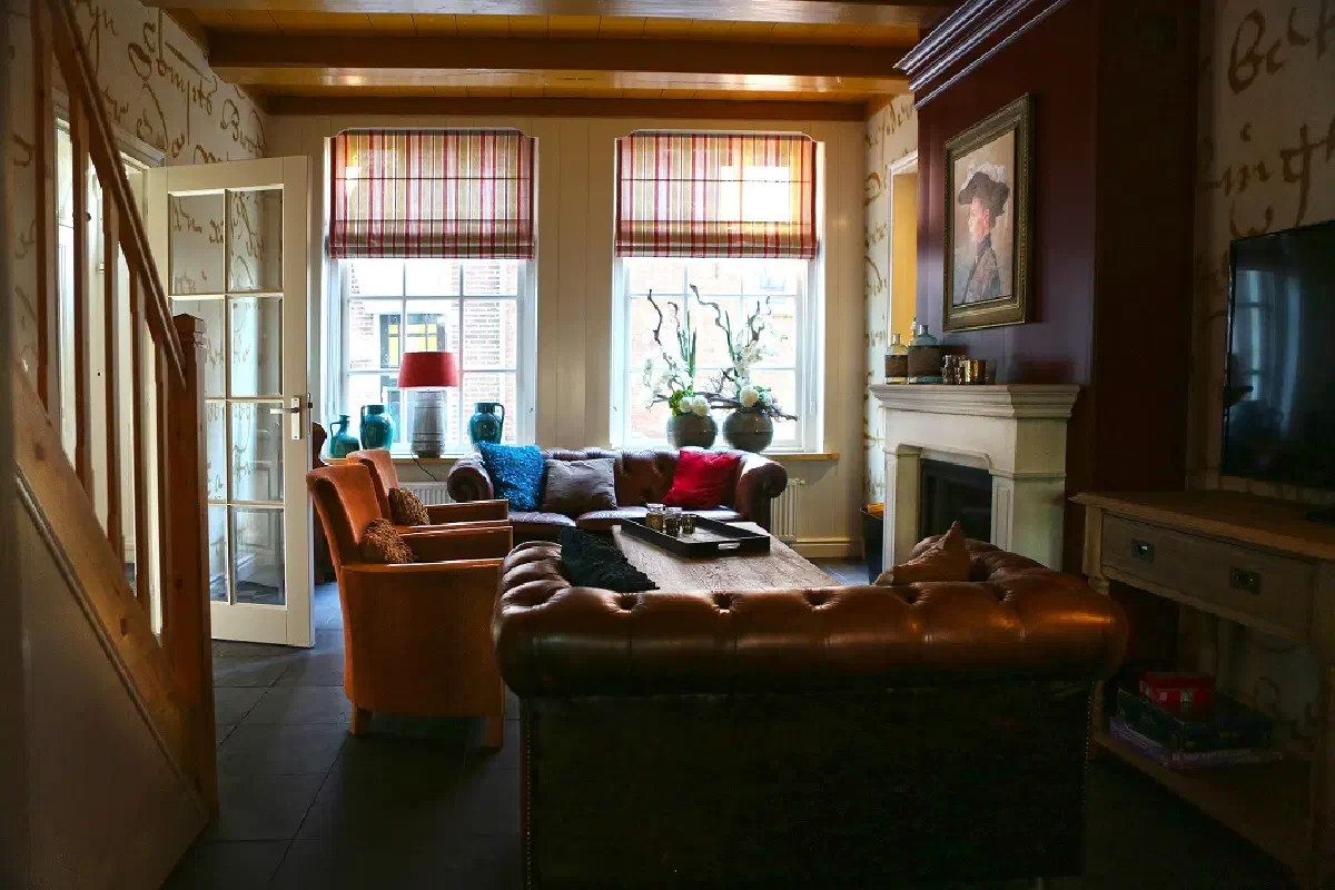 Woonkamer met chesterfieldbank, schouw en tv